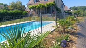 Una piscina rodeada por una valla, con una casa al fondo.