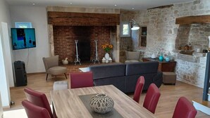 Una sala de estar moderna con chimenea, un comedor con sillas rojas y una pared de piedra.