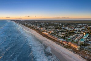An aerial view of a coastal town with beachfront properties, a marina, and a road running parallel to the beach. - Stay Salty (Panama City Beach)