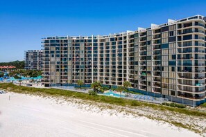A modern hotel with multiple floors, large windows, and a pool area. - Edgewater Tower 2 Unit 505 (Panama City Beach)