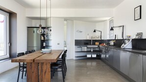 Een moderne keuken met een houten eettafel, zwarte stoelen en roestvrijstalen apparatuur.