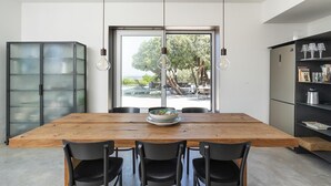 Een moderne eetruimte met een houten tafel, zwarte stoelen en een groot raam met uitzicht op tuinmeubilair.