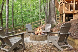 A forested outdoor area with a fire pit and Adirondack chairs. - Cabin with Hot Tub, Firepit, Dog park (Dahlonega)