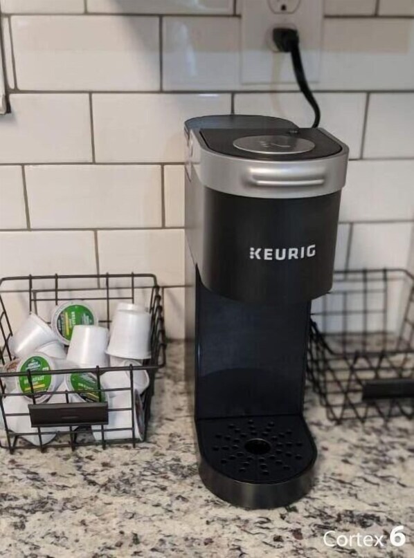 Een Keurig koffiezetapparaat op een aanrecht, met een houder voor koffiekapsules met verschillende soorten capsules.