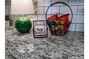Een aanrecht met een groene lamp, een mand met lekkernijen en een bordje met de tekst 'Snacks, zelfbediening'.