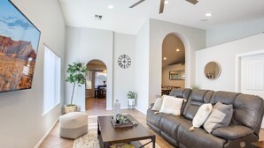 A spacious living room with a leather sofa, a coffee table, and a large painting of a desert landscape.