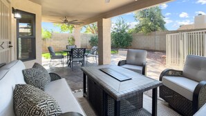 A covered patio area with outdoor furniture, a ceiling fan, and a view of the backyard.