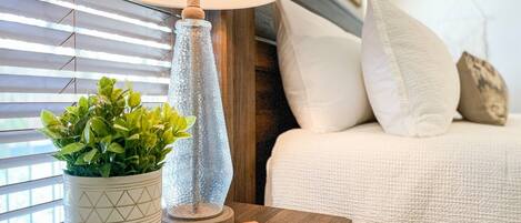 A neatly arranged bedside table with a lamp, a potted plant, and a small book.