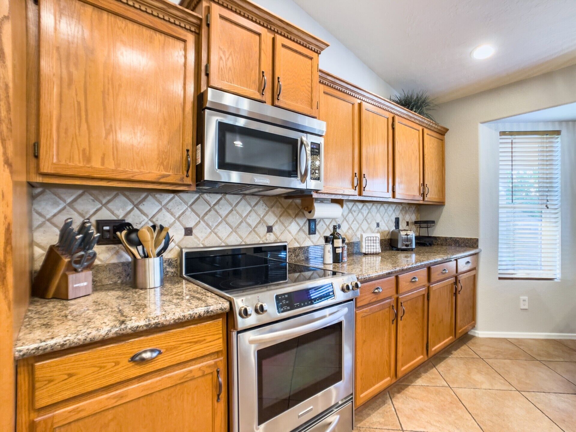 A kitchen with wooden cabinets, a microwave, a stove, and a granite countertop.
