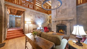 A spacious room with a stone fireplace, wooden furniture, and a staircase leading to an upper level. - Magnificent Estate, Vineyard Views, Pool and  Spa - Sonoma Valley Farm Stay (Sonoma)
