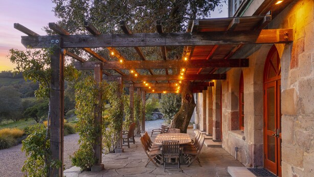 A covered outdoor patio with stone flooring, wooden furniture, and string lights. - Magnificent Estate, Vineyard Views, Pool and  Spa - Sonoma Valley Farm Stay (Sonoma)