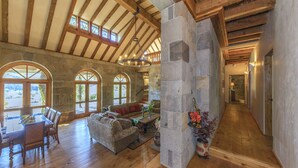 A spacious interior with wooden beams, stone walls, and a dining area with a table and chairs. - Magnificent Estate, Vineyard Views, Pool and  Spa - Sonoma Valley Farm Stay (Sonoma)