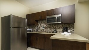 Una cocina moderna con gabinetes de madera oscura, un refrigerador de acero inoxidable, un microondas, un tostador y un salpicadero de azulejos.
