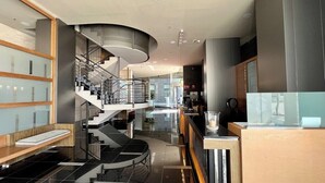 Eine moderne Hotelhalle mit einer geschwungenen Treppe, einem Empfangsbereich und einer Sitzecke.
