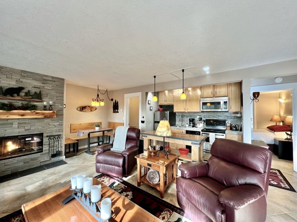 A modern living room with a fireplace, leather chairs, and a dining area.