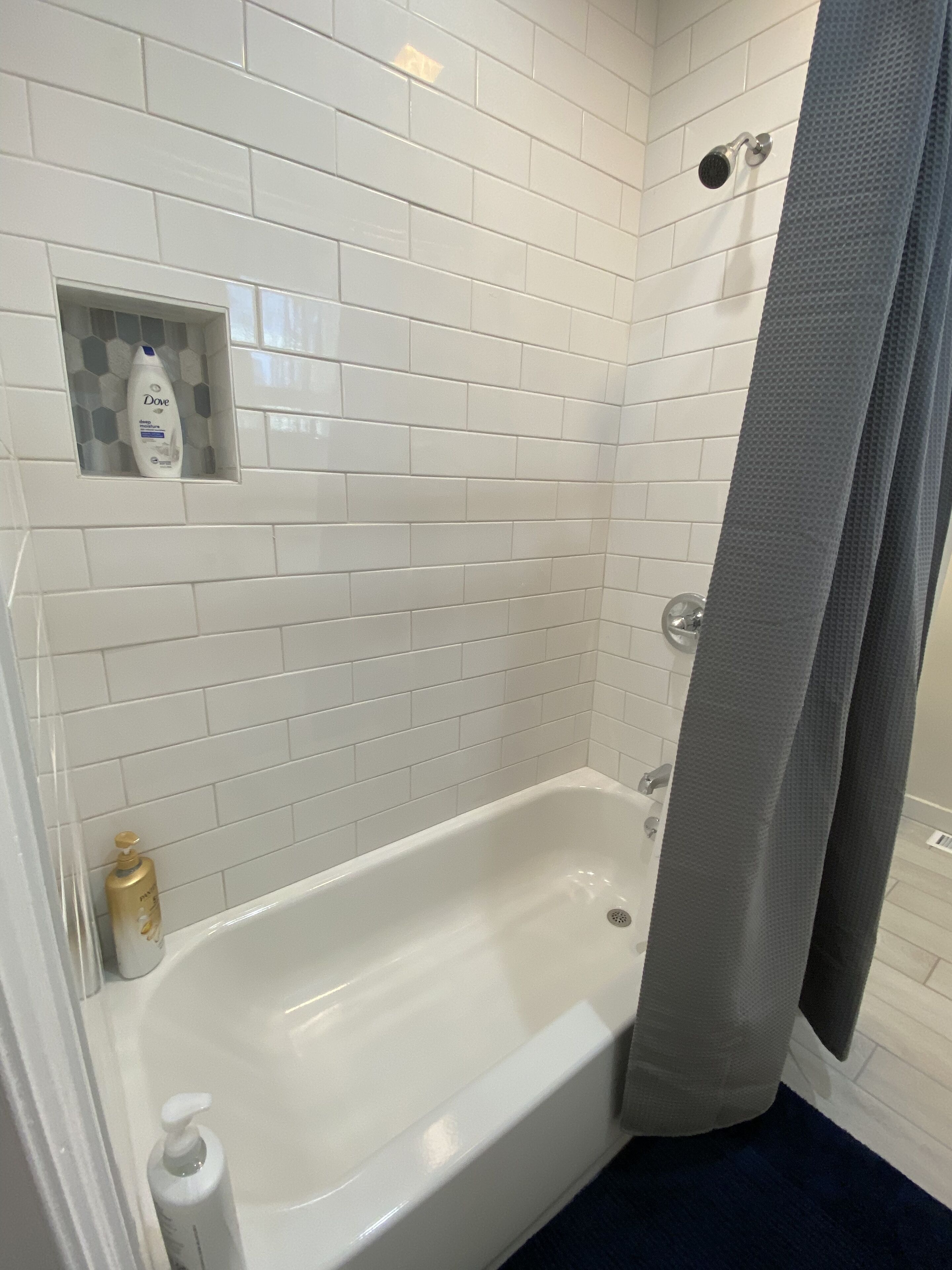 Un baño con una bañera blanca, un cortinón de ducha y artículos de aseo en la pared.