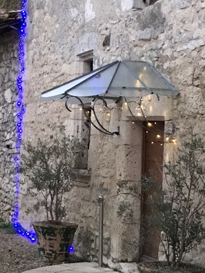 A rustic stone building with a metal umbrella structure and string lights.