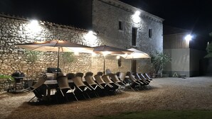 An outdoor dining area with stone walls, a grill, and umbrellas providing shade. - Large gite sleeps 23 with all comforts (Lalandusse)