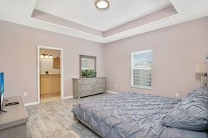 Ein Schlafzimmer mit Bett, Kommode und einer Tür zu einem Badezimmer.