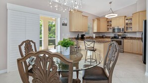 Una cocina moderna con armarios de madera, una mesa de comedor de vidrio y una araña.