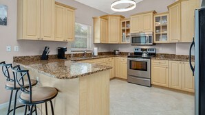 Una cocina con encimeras de granito, armarios de madera, horno de acero inoxidable y microondas.