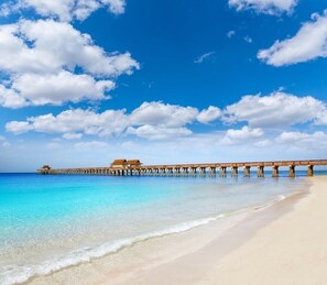 A beach with a wooden pier extending into the ocean, a small building at the end of the pier, and clear blue skies with scattered clouds. - Modern 4- bedroom just 5 mins from gorgeous Naples beach (Naples)