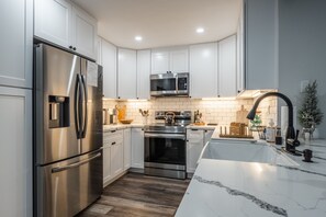 A modern kitchen with white cabinets, stainless steel appliances, and a marble countertop. - Bright & airy, serene, clean & comfy Snowcreek IV (Mammoth Lakes)