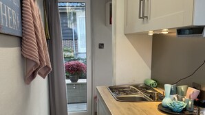 A modern kitchen with a wooden countertop, stainless steel appliances, and a sliding glass door leading to a balcony with flowers. - Sleeping on the water (Zwartsluis)