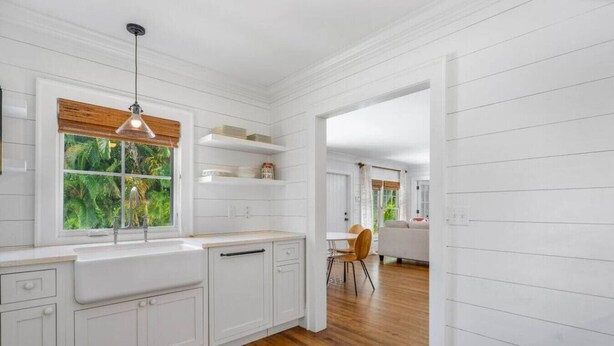 A modern kitchen with white cabinetry, a wooden countertop, and a window with a view of greenery. - The "Water House" Cottages (Gulf Stream)