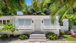 A white house with two doors and a small porch. - The "Water House" Cottages (Gulf Stream)