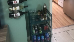 Une cuisine équipée d’un meuble à bouteilles, d’une étagère avec des objets décoratifs et d’un réfrigérateur.