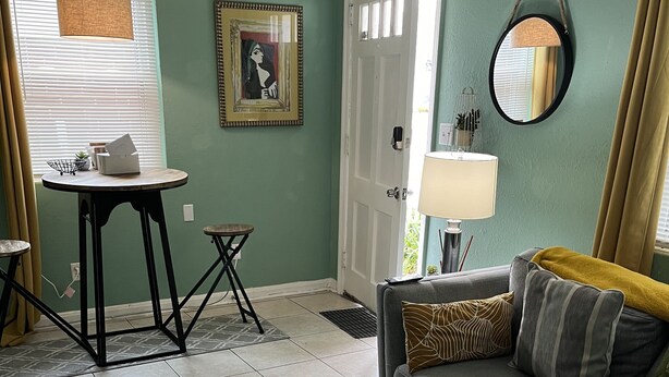 Un salon avec un canapé gris, une petite table ronde et un tapis vert.