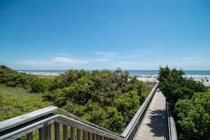 A wooden boardwalk leading to a beach with dense greenery on either side. - $150 activities - E-gift card when you book - Stunning Oceanfront Retreat in Gated Community | M2303 (Myrtle Beach)