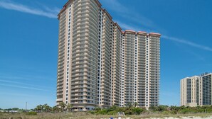 A high-rise hotel with multiple balconies, located near a beach with palm trees. - $150 activities - E-gift card when you book - Stunning Oceanfront Retreat in Gated Community | M2303 (Myrtle Beach)