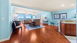 A spacious living room with a dining area, a kitchen with wooden cabinets, and a view of the outdoors. - $150 activities - E-gift card when you book - Stunning Oceanfront Retreat in Gated Community | M2303 (Myrtle Beach)