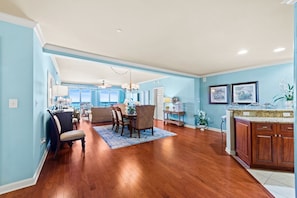 A spacious living room with a dining area, a kitchen with wooden cabinets, and a view of the outdoors. - $150 activities - E-gift card when you book - Stunning Oceanfront Retreat in Gated Community | M2303 (Myrtle Beach)