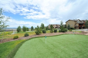 Un terrain de golf bien entretenu, doté d’un green d’entraînement, entouré d’arbres matures et bordé d’un quartier résidentiel avec des maisons.