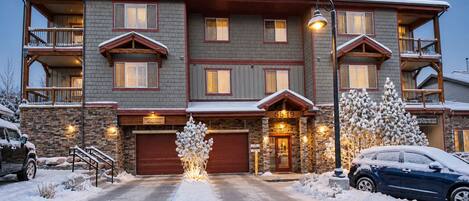 A multi-story building with a stone facade, multiple balconies, and a garage entrance.