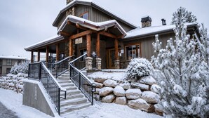 Un lodge con facciata in pietra, travi in legno e una scala che conduce all'ingresso.