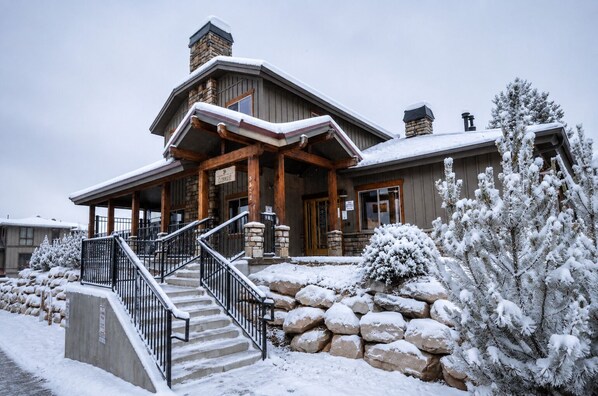 Un chalet doté d’une façade en pierre, de poutres en bois et d’un escalier menant à l’entrée.