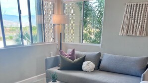 Ein modernes Wohnzimmer mit einem Glastisch, einem grauen Sofa und weißen Stühlen.