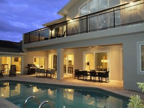 A two-story building with a swimming pool, outdoor seating, and a balcony. - Palm River Estate (Naples)