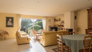 A spacious living room with a sofa set, a dining table, and a television. - Lenerie - 800m plage - Wifi - Parking (Préfailles)