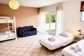 A room with bunk beds, a sofa, a bedside table with a lamp, and a window with curtains. - Lenerie - 800m plage - Wifi - Parking (Préfailles)
