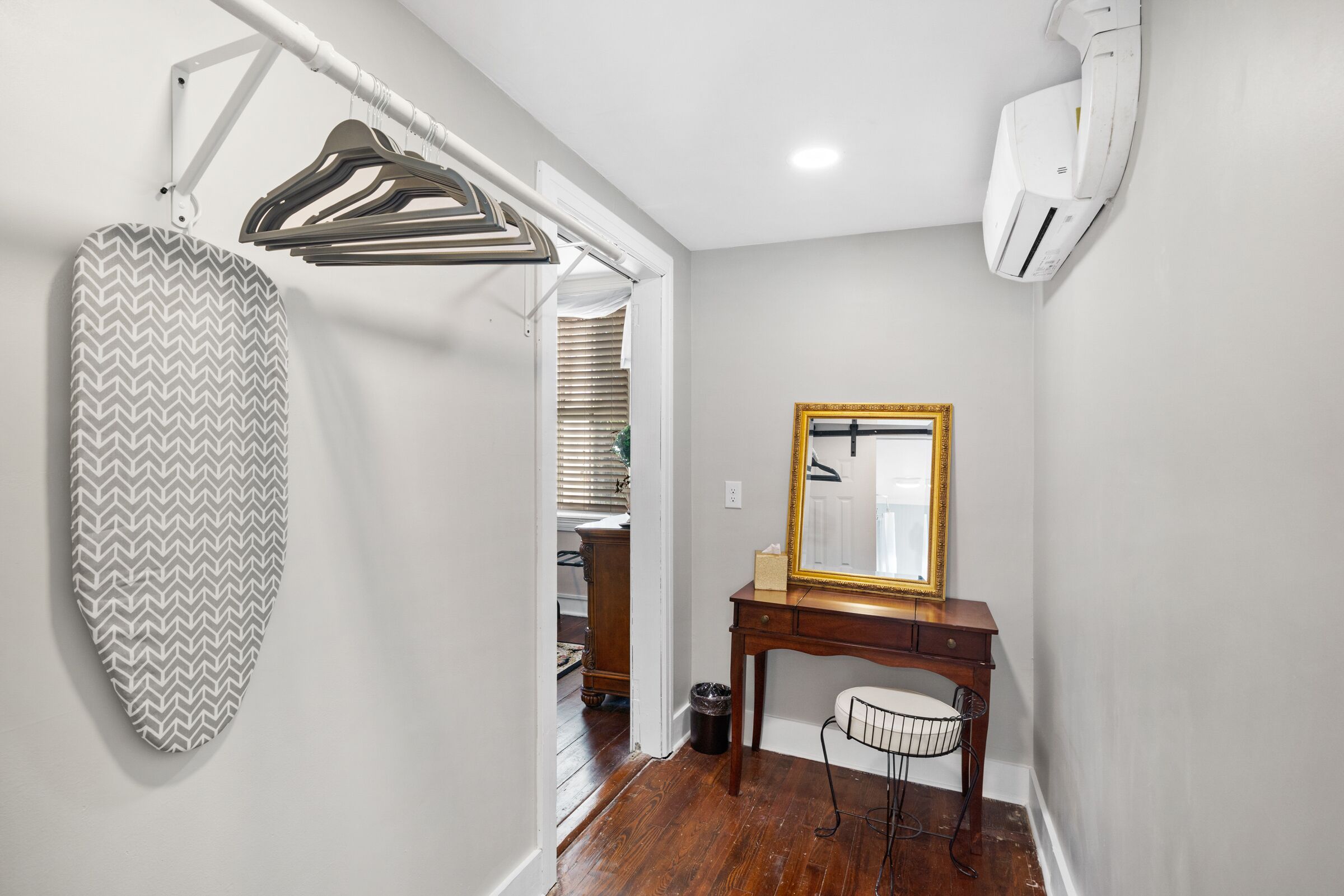 A bathroom with a wooden vanity, a mirror with a gold frame, and a towel rack.