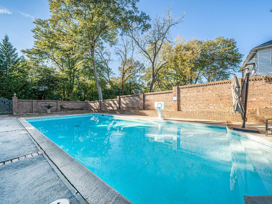 Una piscina rectangular amb una paret de maó i un cèrcol de bàsquet al costat dret.
