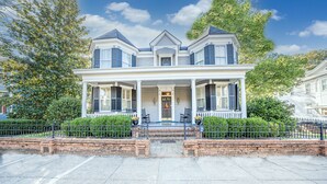 A two-story house with a porch, brick steps, and a fence. - The Inn on North Jefferson (Milledgeville)