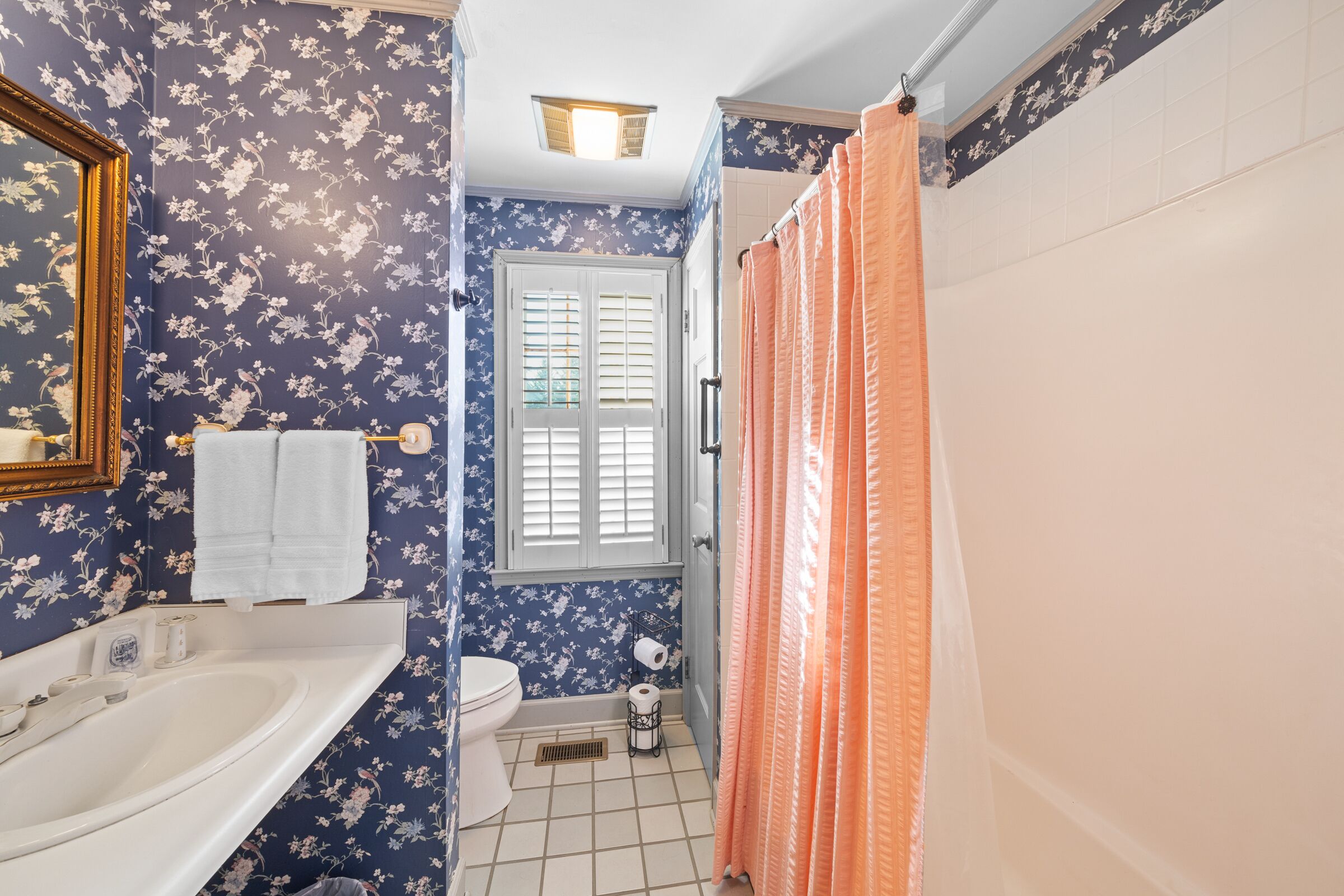 Een badkamer met een witte wastafel, toilet en douchegordijn.
