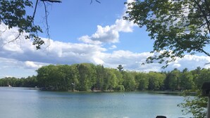 En träaltan med utsikt över en stilla sjö, där en båt ligger förtöjd vid stranden.