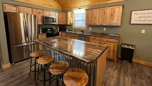 A kitchen with wooden cabinets, stainless steel appliances, a granite countertop, and a bar stool area.